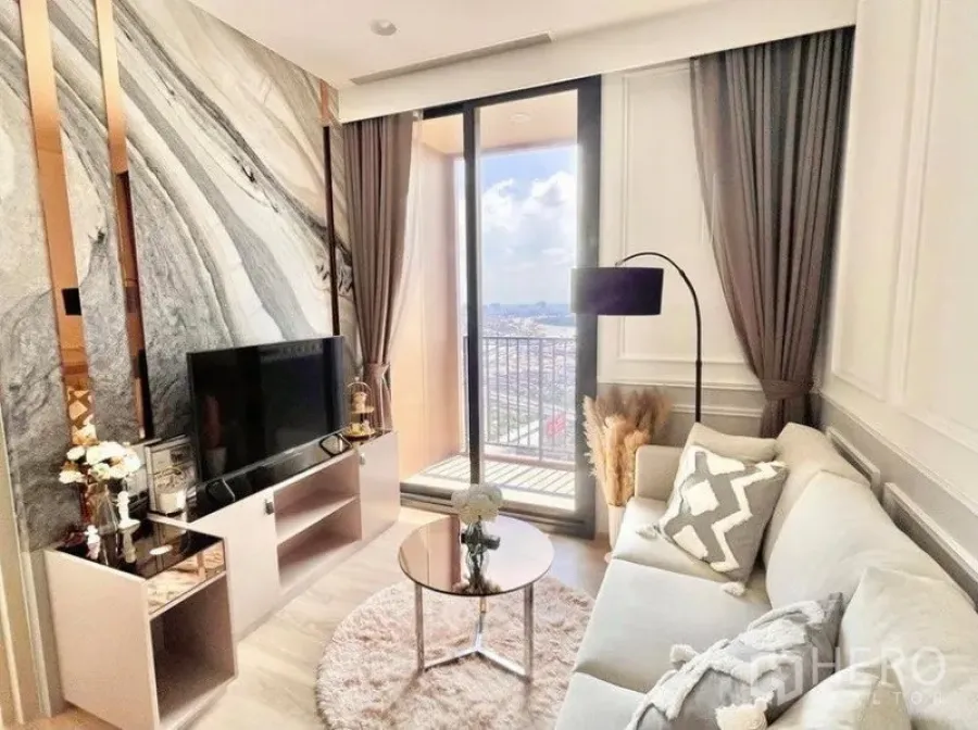 คอนโด ให้เช่าในKhlong Toei, Bangkok - ห้องนั่งเล่นสว่าง ผนังลายหินอ่อน มุมทีวี และประตูกระจกบานเลื่อนออกสู่ระเบียงชมวิวเมือง