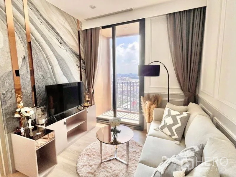 คอนโด ให้เช่าในKhlong Toei, Bangkok - ห้องนั่งเล่นสว่าง ผนังลายหินอ่อน มุมทีวี และประตูกระจกบานเลื่อนออกสู่ระเบียงชมวิวเมือง