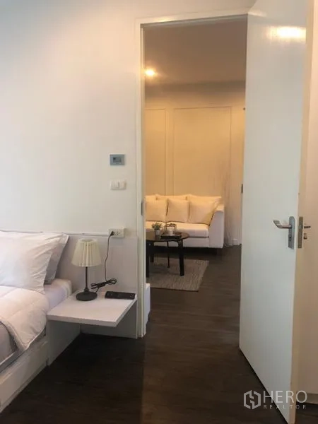 คอนโด ให้เช่าในPathum Wan, Bangkok - มุมมองจากห้องนอนไปยังห้องนั่งเล่นผ่านประตูเปิด เห็นโซฟาและโต๊ะกาแฟ