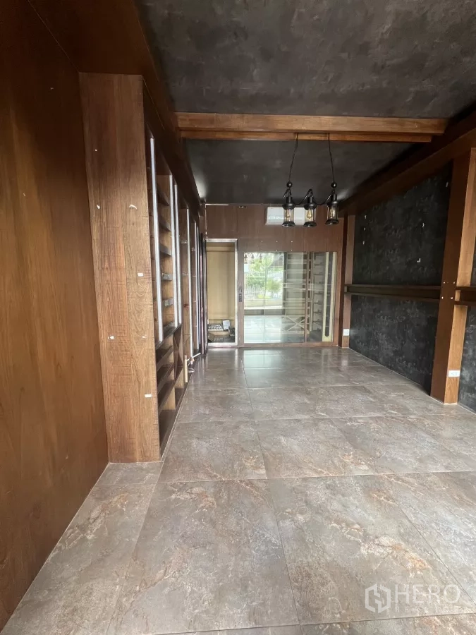 พื้นที่ขายปลีก ให้เช่า - ห้องร้านค้าขนาดกะทัดรัด พื้นกระเบื้องลายหิน ชั้นวางไม้บิวท์อิน และโคมไฟแขวน