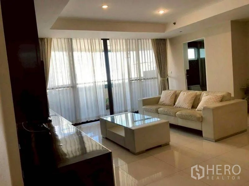 公寓 for rent or sale in Watthana, Bangkok - 明亮客厅，米色沙发、玻璃茶几与落地窗帘。