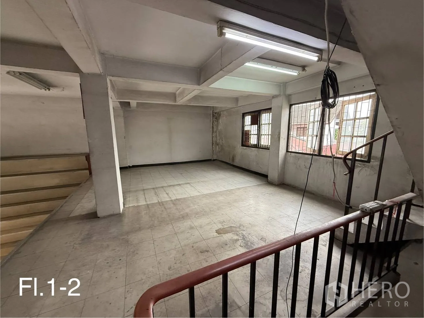 Shophouse for rent in Bang Na, Bangkok - Open mezzanine and first-floor area with windows, fluorescent lighting and a metal handrail stair.