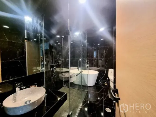 คอนโด ขาย - ห้องน้ำโมเดิร์น มีตู้ Shower กระจก อ่างอาบน้ำ เคาน์เตอร์ล้างมือ และผนังหินสีเข้ม
