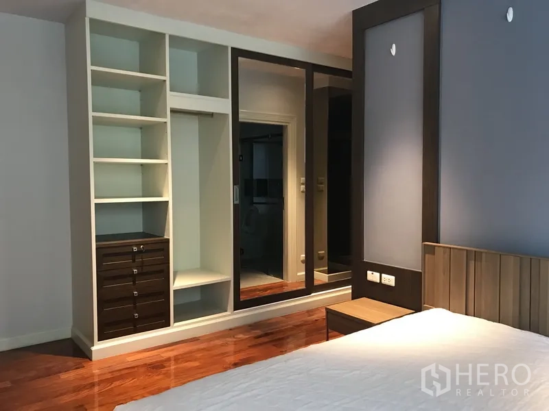 Apartment for rent in Pathum Wan, Bangkok - Bedroom with built-in wardrobe, open shelving and mirrored sliding doors.