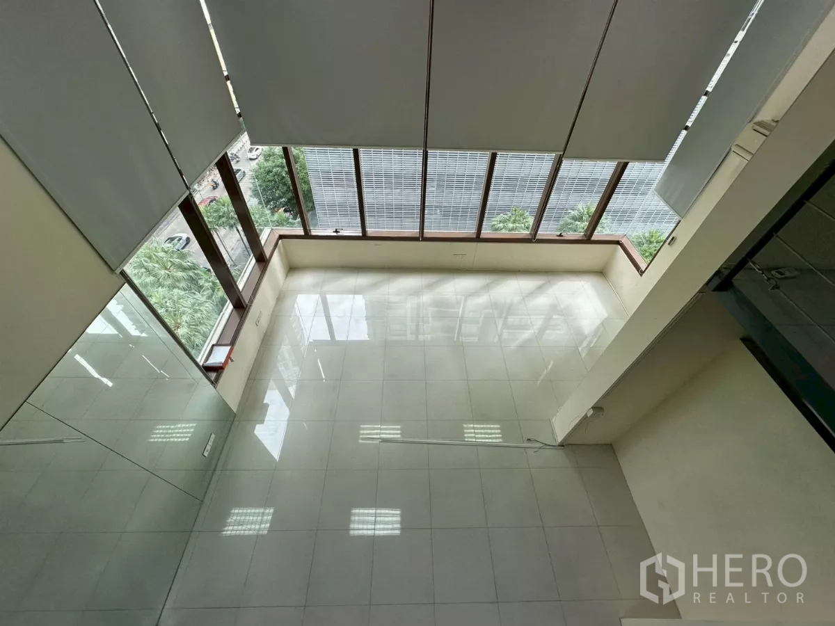 สำนักงาน ให้เช่าในKhlong Toei, Bangkok - ภาพมุมสูงจากชั้นลอยลงสู่โถงคู่ความสูง พร้อมกระจกเต็มผนังและต้นไม้ริมถนน