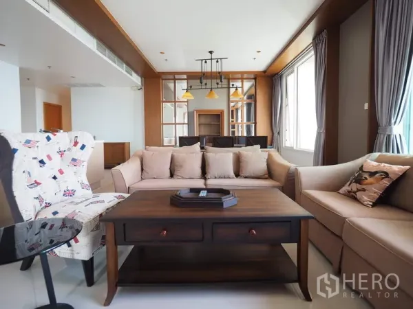 Condominium for rent in Sathon, Bangkok - Spacious living room with beige sofas, wooden coffee table and glass partition to the dining area.
