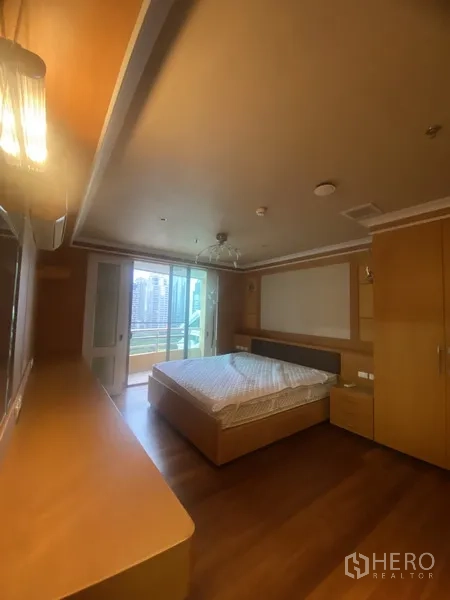 Condominium for rent in Pathum Wan, Bangkok - Primary bedroom with balcony access, city outlook, built-in storage and warm timber finishes.