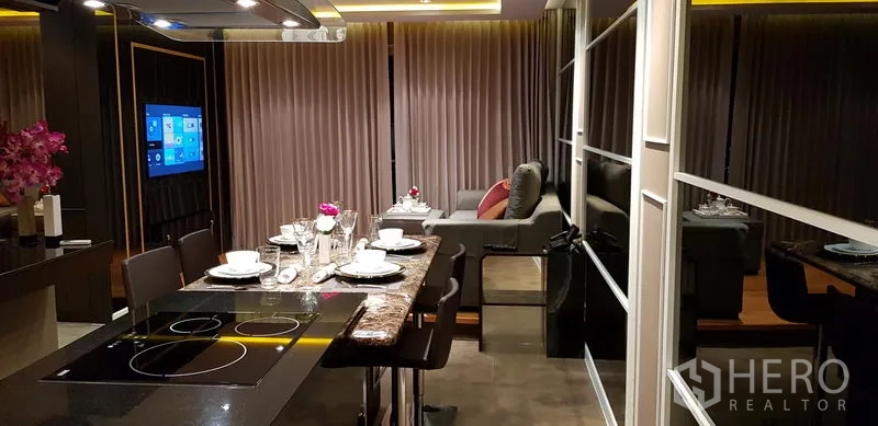 公寓 出租在Ratchathewi, Bangkok - 厨房岛台与餐桌面向客厅，落地窗帘与电视。