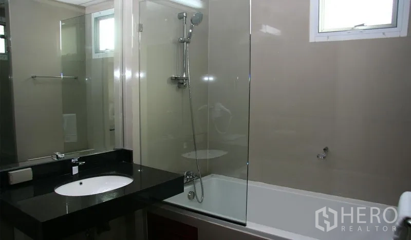 Apartment for rent in Khlong Toei, Bangkok - Bathroom with bathtub, glass shower screen and black stone vanity top