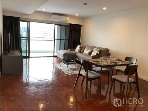 Condominium for rent or sale in Sathon, Bangkok - Bright living and dining area with L-shaped sofa, set table, TV stand and sliding doors to a balcony with city view.