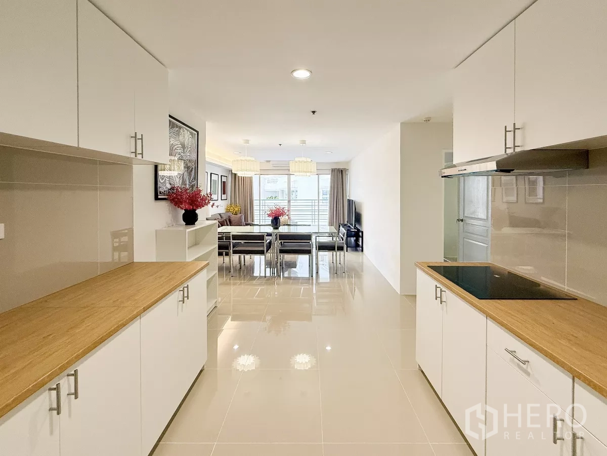 公寓 出租在Khlong Toei, Bangkok - 白色走廊式厨房，木质台面，连通餐客区。