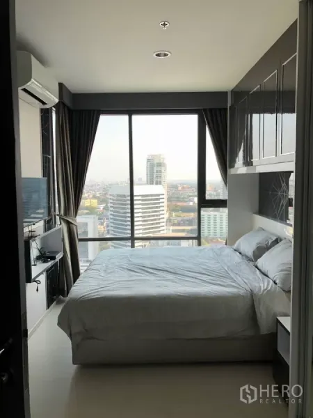 Condominium for rent in Khlong Toei, Bangkok - Bedroom with floor-to-ceiling windows and panoramic Bangkok skyline view.
