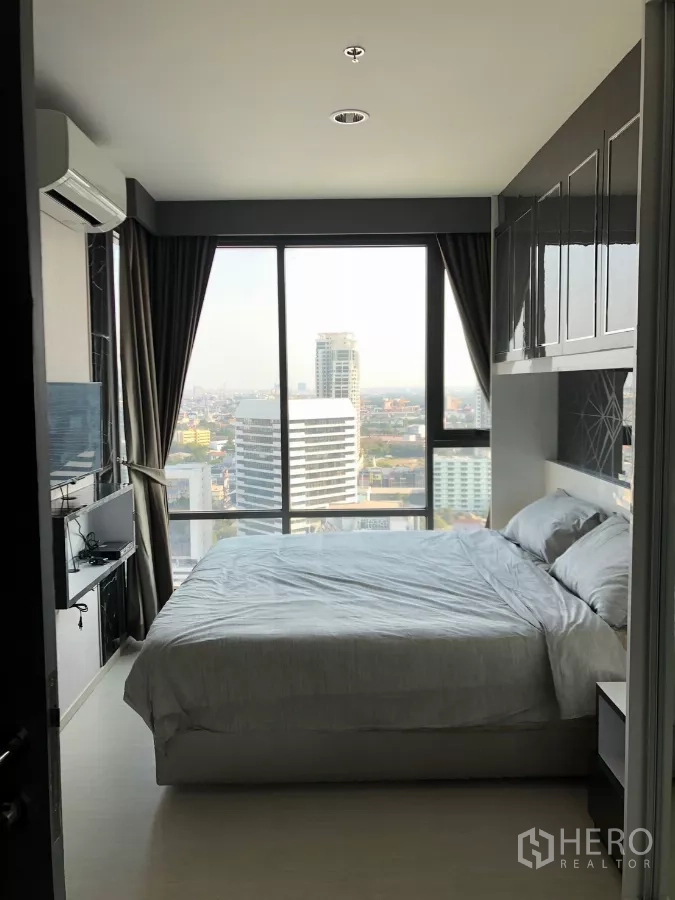 Condominium for rent in Khlong Toei, Bangkok - Bedroom with floor-to-ceiling windows and panoramic Bangkok skyline view.