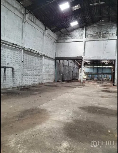 Warehouse for rent in Phra Samut Chedi, Samut Prakan - Long interior aisle showing block walls, steel trusses and clear column‑free floor space.
