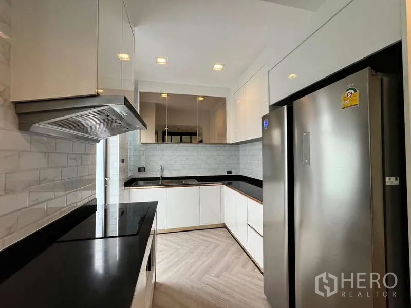 บ้าน ให้เช่าหรือขายในLat Krabang, Bangkok - ครัวรูปตัว U ตู้สีขาวเงา ตู้เย็นสแตนเลส และเตาไฟฟ้า