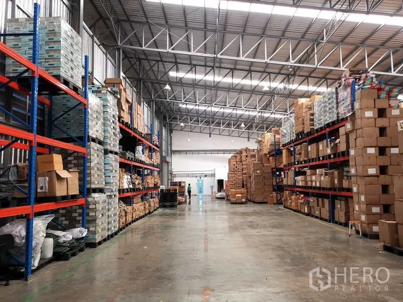 คลังสินค้า ให้เช่าหรือขายในNonthaburi - ทางเดินโกดังกว้างเรียงรายด้วยชั้นเหล็กสูงและกล่องสินค้า