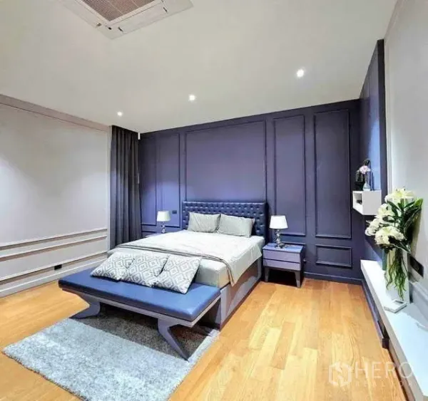 บ้าน ขายในKhlong Sam Wa, Bangkok - ห้องนอนสไตล์ร่วมสมัย ผนังกรุสีกรมท่า มีม้านั่งปลายเตียง โต๊ะข้าง และพื้นไม้โทนอุ่น