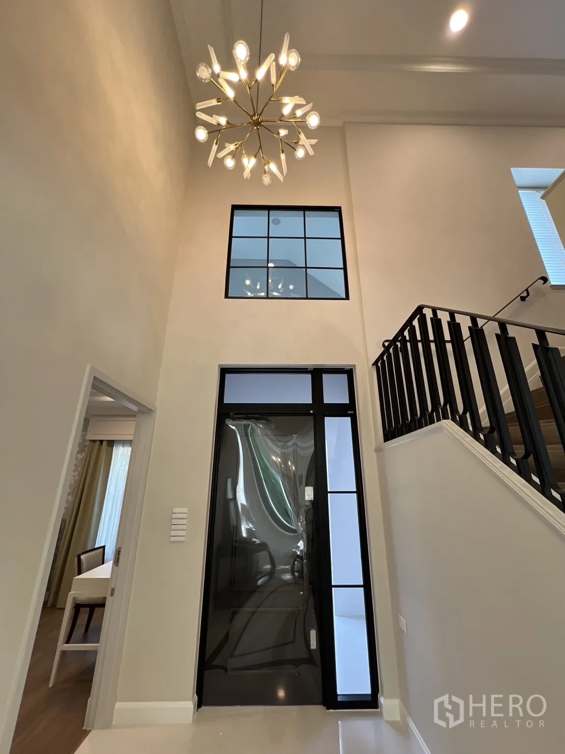 Detached House for rent in Saphan Sung, Bangkok - Double‑height foyer with statement chandelier and black stair railing.