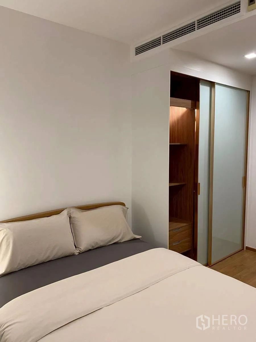 Condominium for rent in Watthana, Bangkok - Bedroom with double bed and sliding frosted-glass closet doors.
