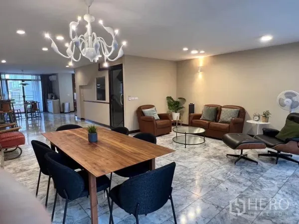 Townhouse for sale in Suan Luang, Bangkok - Open‑plan living and dining area with wooden table, chandelier and large windows.