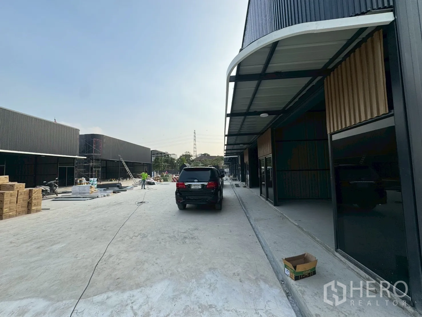 Warehouse for rent in Suan Luang, Bangkok - New-build black metal warehouse units with covered loading bays and a wide concrete driveway.