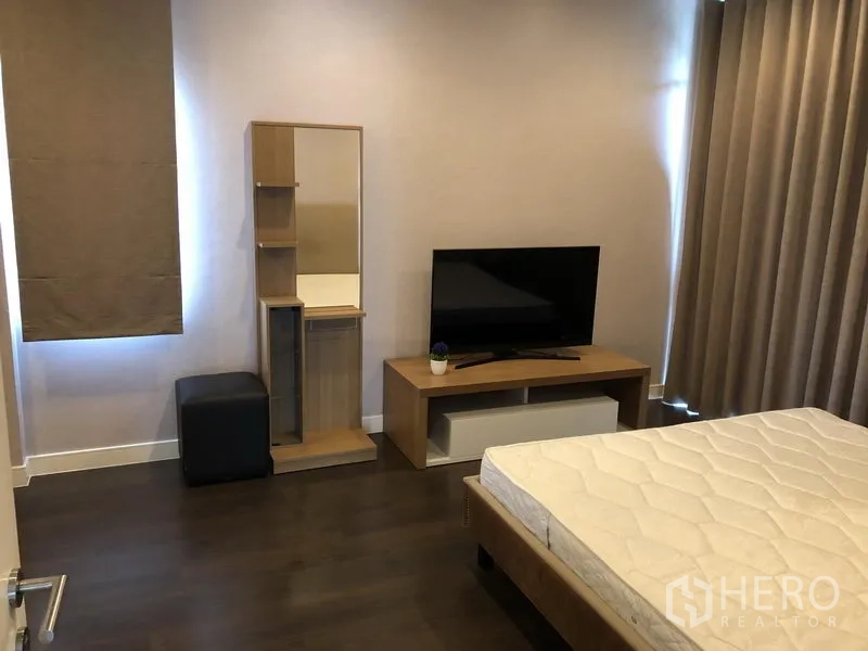 Detached House for rent or sale in Bang Kapi, Bangkok - Master bedroom corner with TV console, dressing mirror and tall curtains.