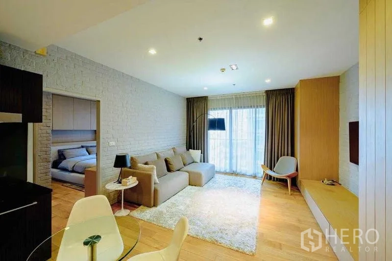 Condominium for rent in Watthana, Bangkok - Living room facing bedroom entrance and kitchenette, wood flooring throughout.