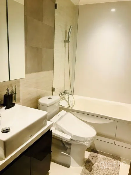 Condominium for rent or sale in Watthana, Bangkok - Modern bathroom with bathtub and shower combo, vanity and toilet in neutral tones.