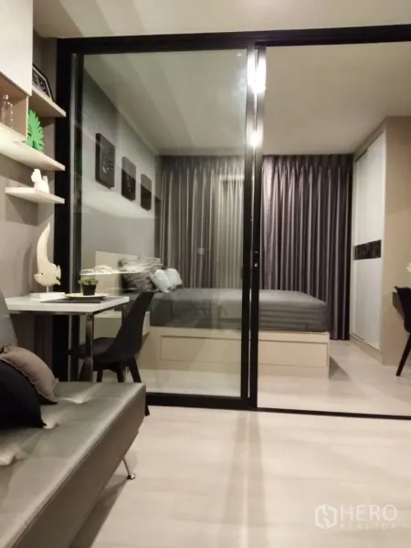 Condominium for rent in Huai Khwang, Bangkok - Modern condo living room with glass sliding partition opening to a cozy bedroom