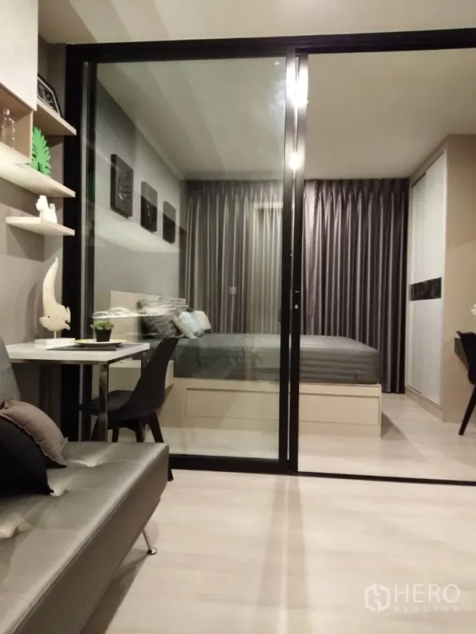 Condominium for rent in Huai Khwang, Bangkok - Modern condo living room with glass sliding partition opening to a cozy bedroom