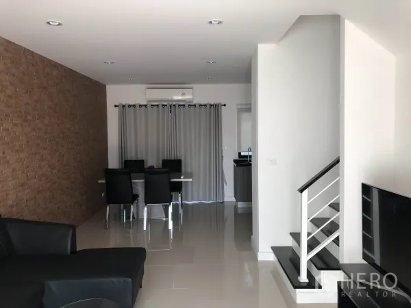 ทาวน์เฮาส์ ให้เช่าในBang Kapi, Bangkok - โถงนั่งเล่น–รับประทานอาหารโปร่ง ผนังตกแต่งลายอิฐ พื้นกระเบื้องเงา และบันไดขึ้นชั้นบน