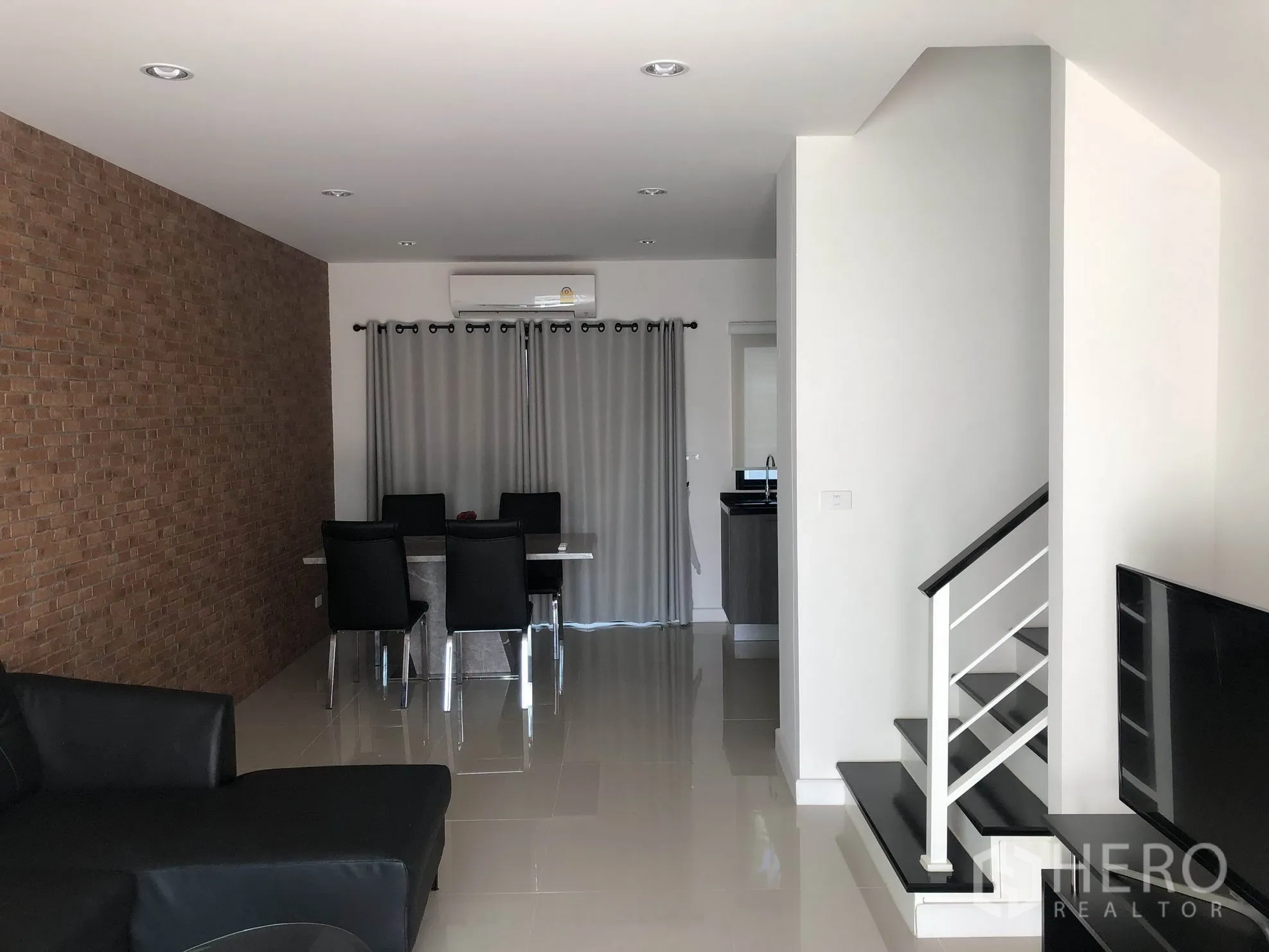ทาวน์เฮาส์ ให้เช่าในBang Kapi, Bangkok - โถงนั่งเล่น–รับประทานอาหารโปร่ง ผนังตกแต่งลายอิฐ พื้นกระเบื้องเงา และบันไดขึ้นชั้นบน