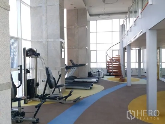 公寓 出租在Pathum Wan, Bangkok - 采光充足的健身房，配跑步机、力量器械和旋转楼梯的公寓设施