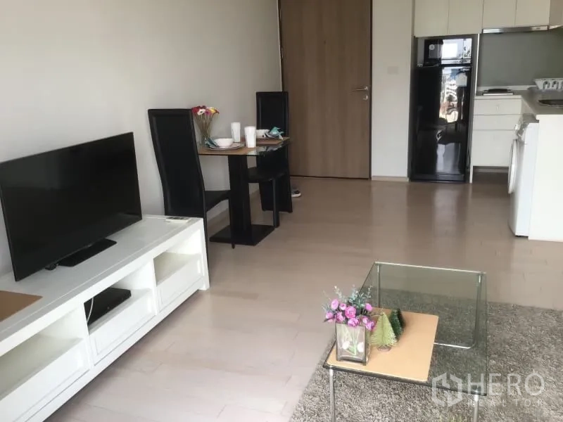 公寓 出租或出售在Watthana, Bangkok - 开放式格局展示餐桌、电视柜以及配有冰箱和洗衣机的小厨房。