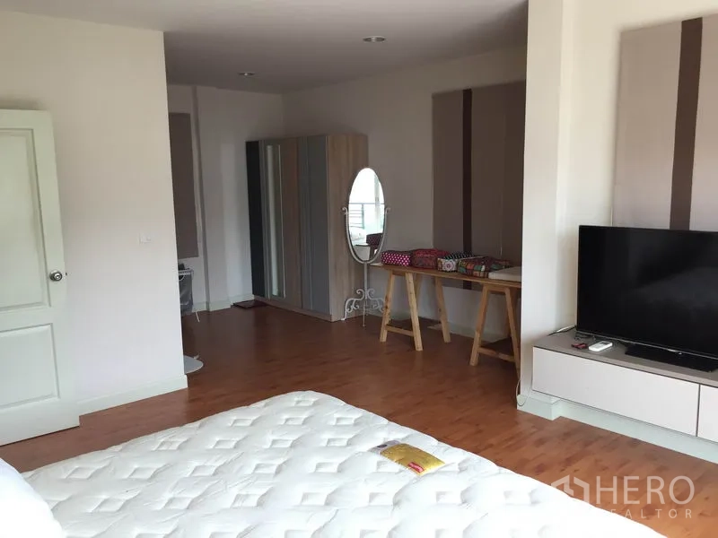 Detached House for rent or sale in Saphan Sung, Bangkok - Wide master suite showing wood floors, TV console, wardrobe and vanity corner.