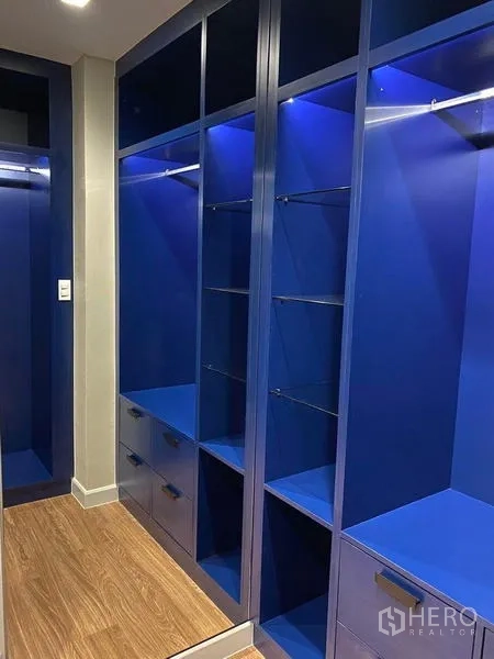 Detached House for rent - Close view of illuminated blue wardrobe with drawers and open shelving.