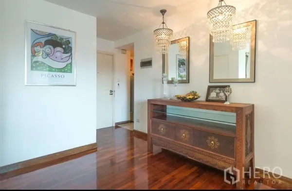 Condominium for rent in Pathum Wan, Bangkok - Entry foyer featuring ornate console, twin chandeliers and mirrors over wooden floors.