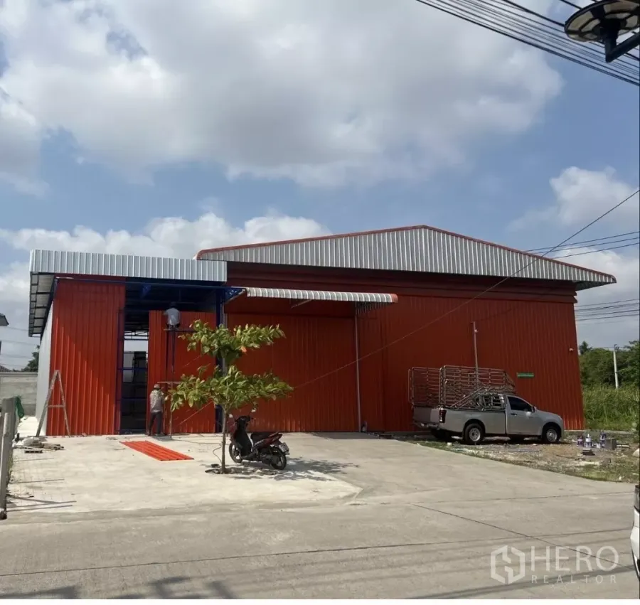 คลังสินค้า ให้เช่าในBang Kruai, Nonthaburi - โกดังโครงเหล็กสีแดงส้ม ประตูบานสไลด์ขนาดใหญ่ พร้อมลานคอนกรีตด้านหน้าในบางกรวย นนทบุรี
