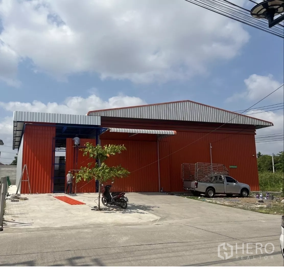 คลังสินค้า ให้เช่าในBang Kruai, Nonthaburi - โกดังโครงเหล็กสีแดงส้ม ประตูบานสไลด์ขนาดใหญ่ พร้อมลานคอนกรีตด้านหน้าในบางกรวย นนทบุรี