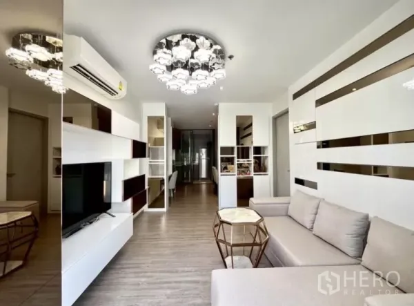 คอนโด ให้เช่าในWatthana, Bangkok - ห้องนั่งเล่นโมเดิร์น บิลท์อิน ชั้นวาง โซฟา แชนเดอเลียร์ และชั้นวางทีวี มองไปทางโถงครัว