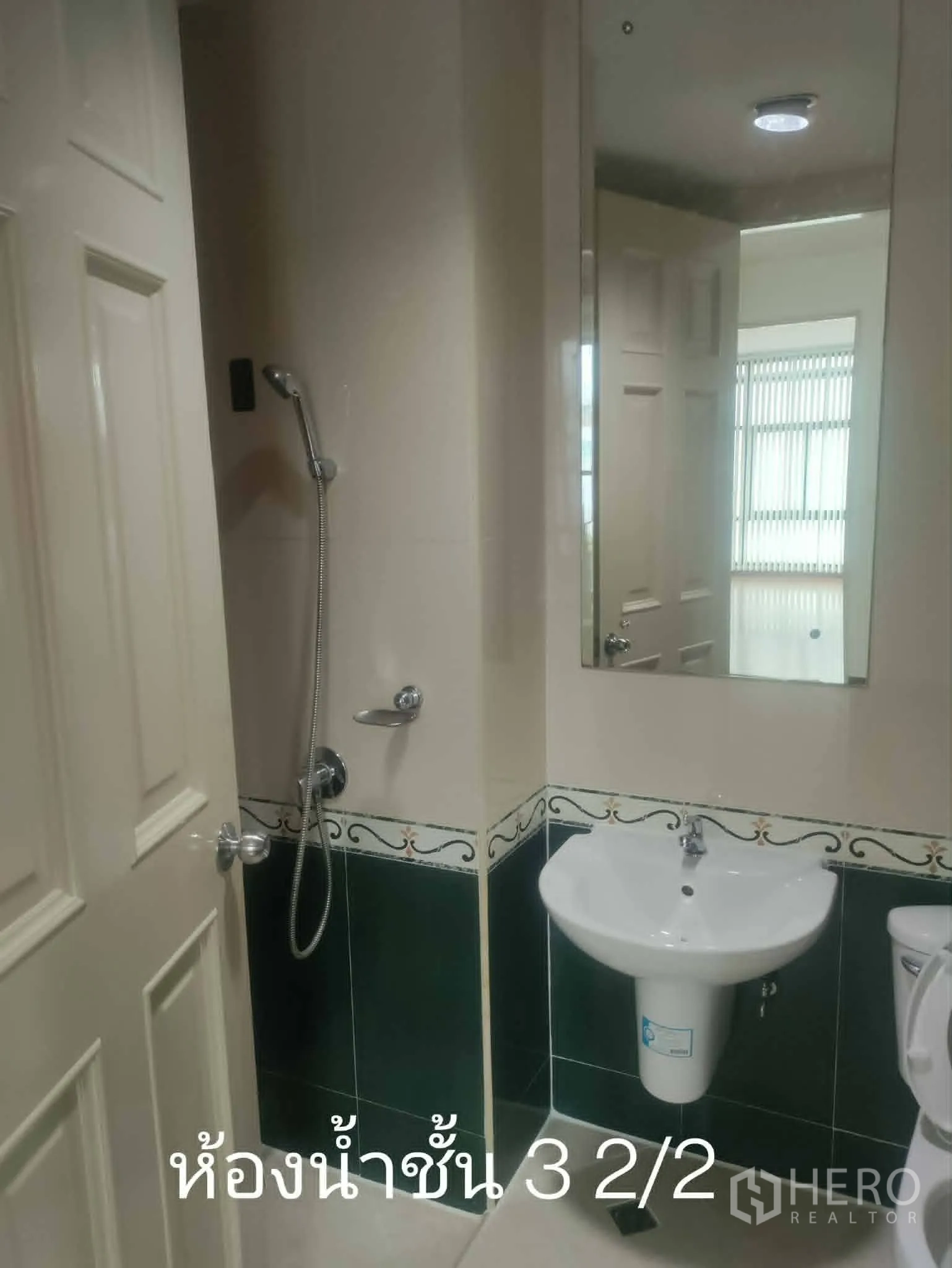 Home Office for rent in Lat Phrao, Bangkok - Compact bathroom with sink, mirror, and handheld shower beside toilet.