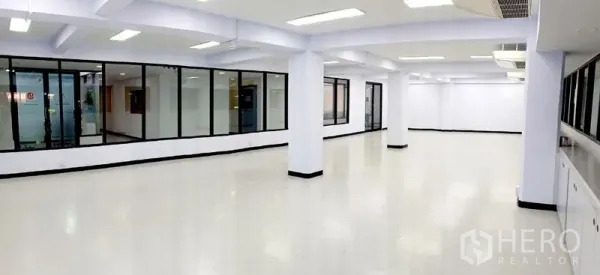 办公空间 出租在Watthana, Bangkok - 明亮的开放式办公室，白色地面与立柱，玻璃隔断会议室。