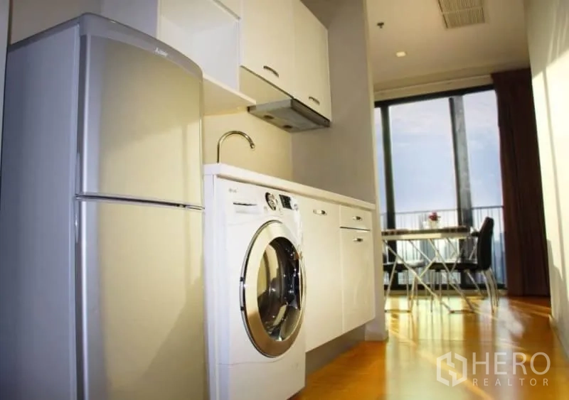 Condominium for rent or sale in Watthana, Bangkok - Compact kitchen with washer and fridge leading to dining space and balcony.