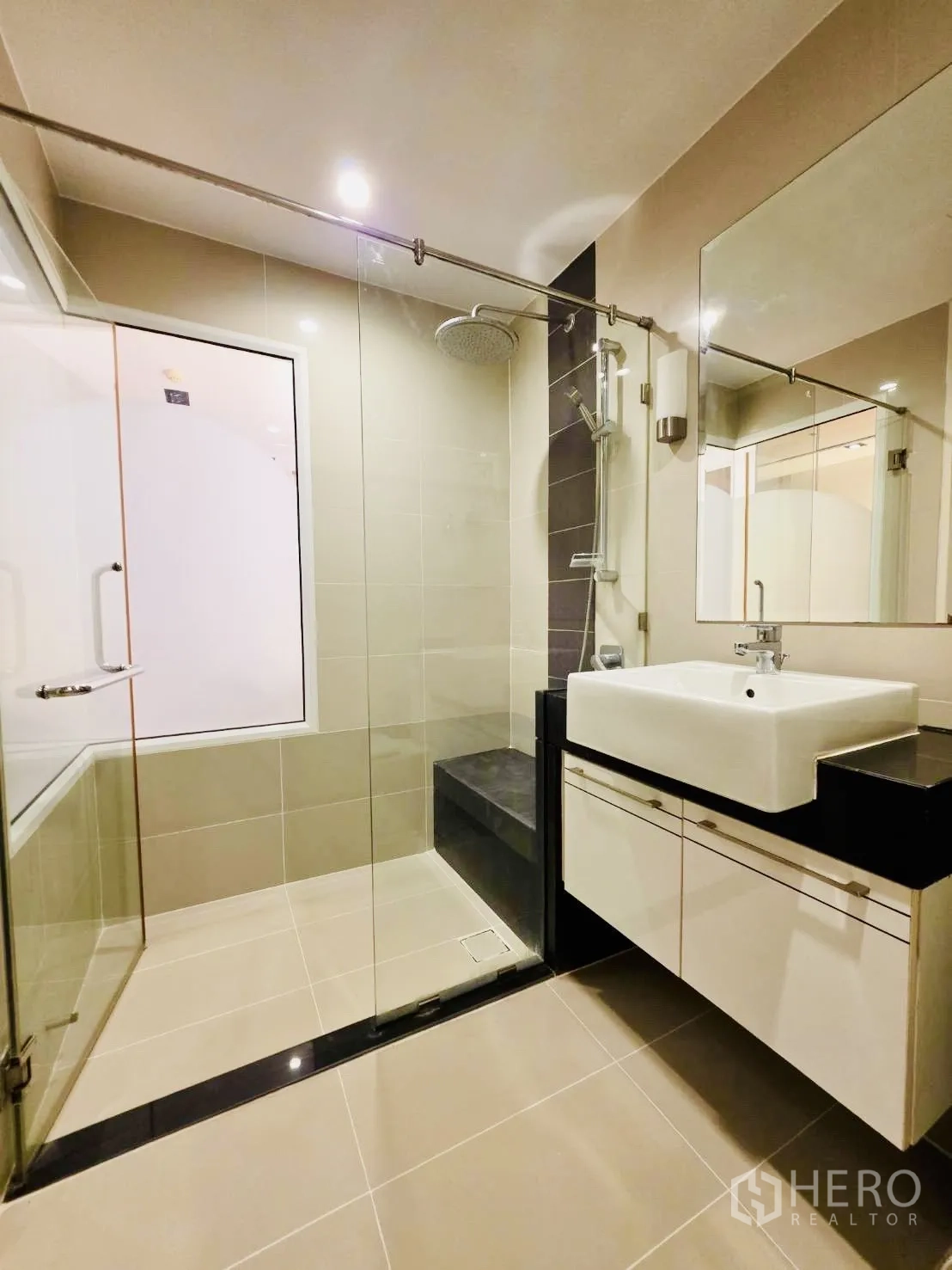 Condominium for rent in Huai Khwang, Bangkok - Modern bathroom featuring a glass shower enclosure with rain shower and a large sink vanity.