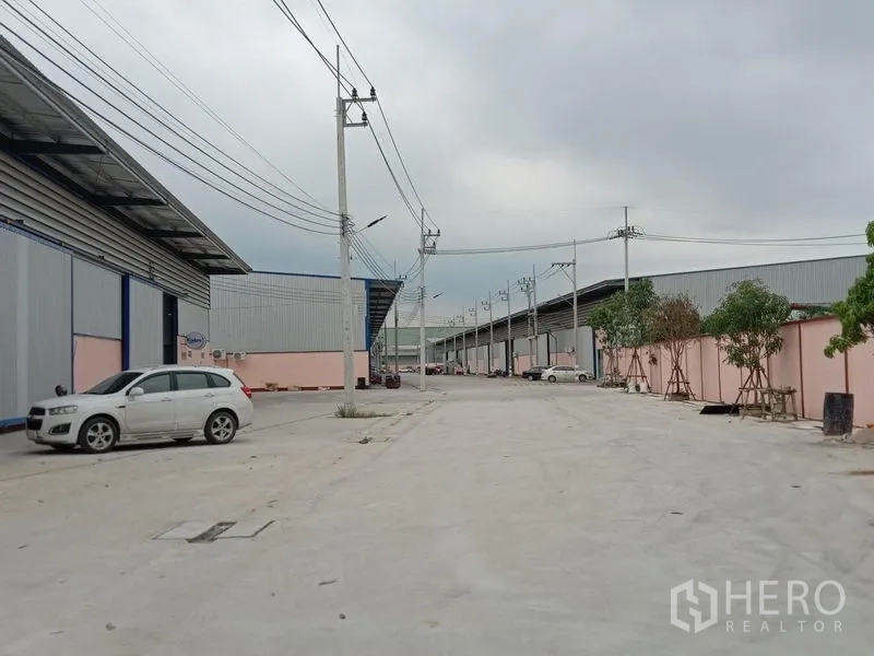Factory for rent in Ban Phaeo, Samut Sakhon - Factory exterior with sliding steel doors, canopies and three‑phase power infrastructure.