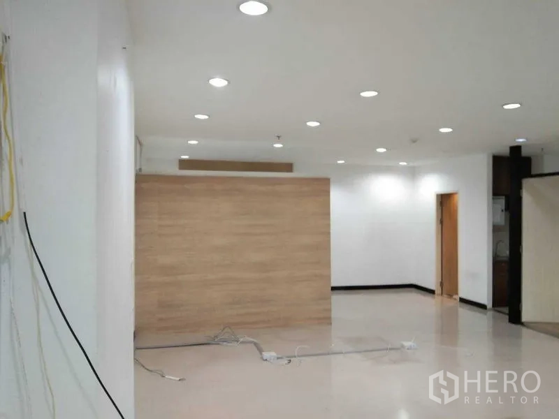 Office Space for rent in Watthana, Bangkok - Bright open-plan office with recessed lighting, wood accent partition and doorway, cables on the glossy floor.