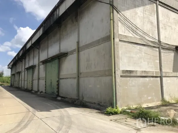 货栈 出租在Mueang Pathum Thani, Pathum Thani - 仓库侧立面，多个装卸门及宽阔车道，适合大货车通行。