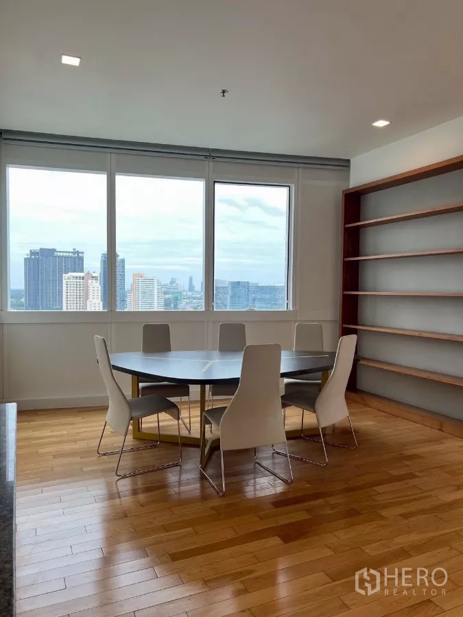 公寓 出租在Khlong Toei, Bangkok - 餐区配六人圆桌，临落地窗与开放式书架，享城市景观。