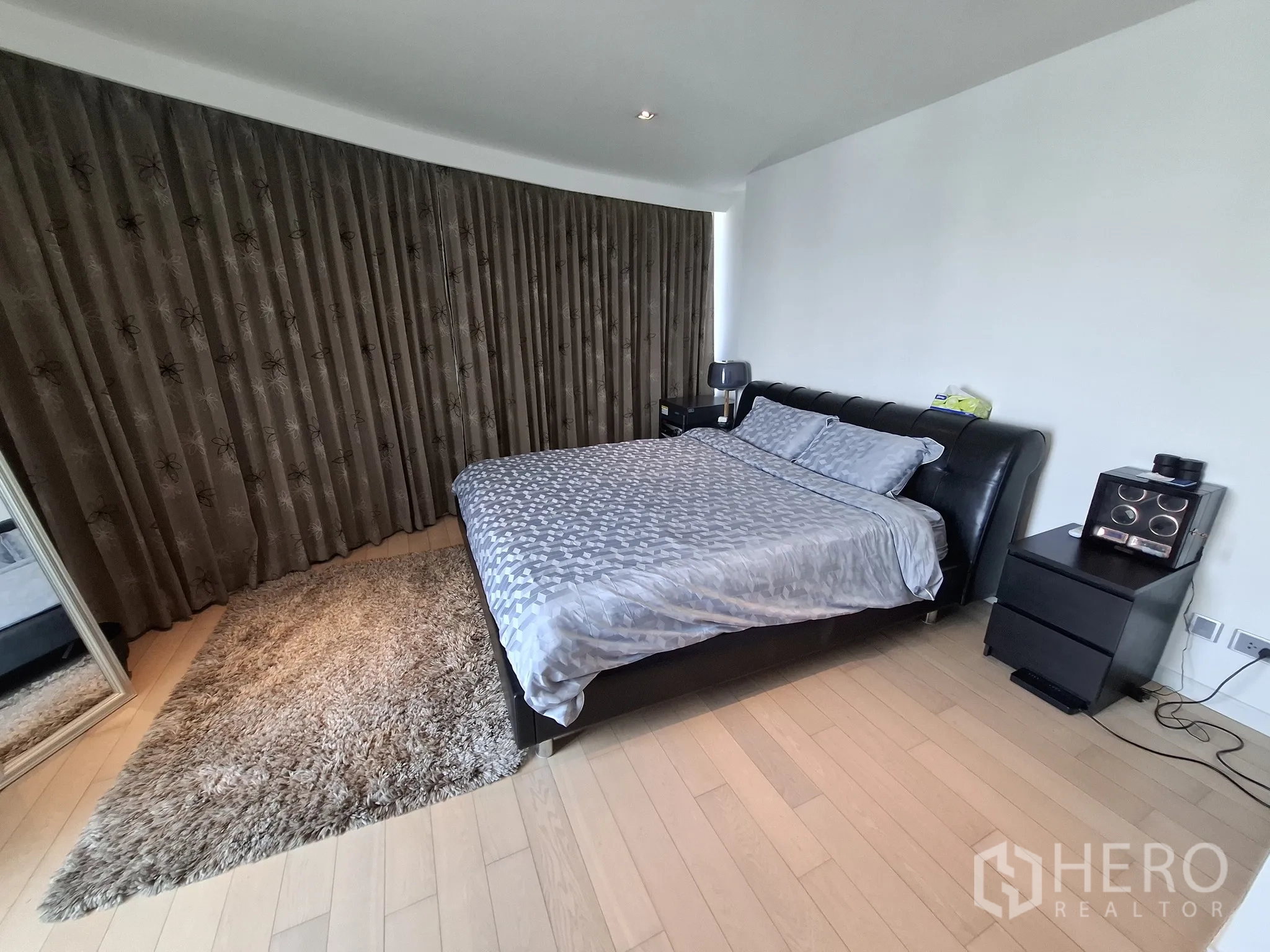 Condominium for rent in Watthana, Bangkok - Guest bedroom with king bed, bedside lamps, and doorway to ensuite.