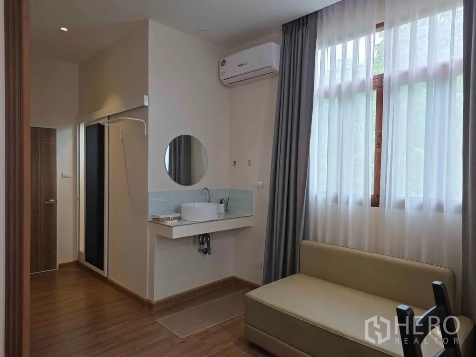 บ้าน ให้เช่าในKhlong Toei, Bangkok - มุมห้องนอนพร้อมอ่างล้างหน้า โซฟาเบด หน้าต่างสูง และเครื่องปรับอากาศ